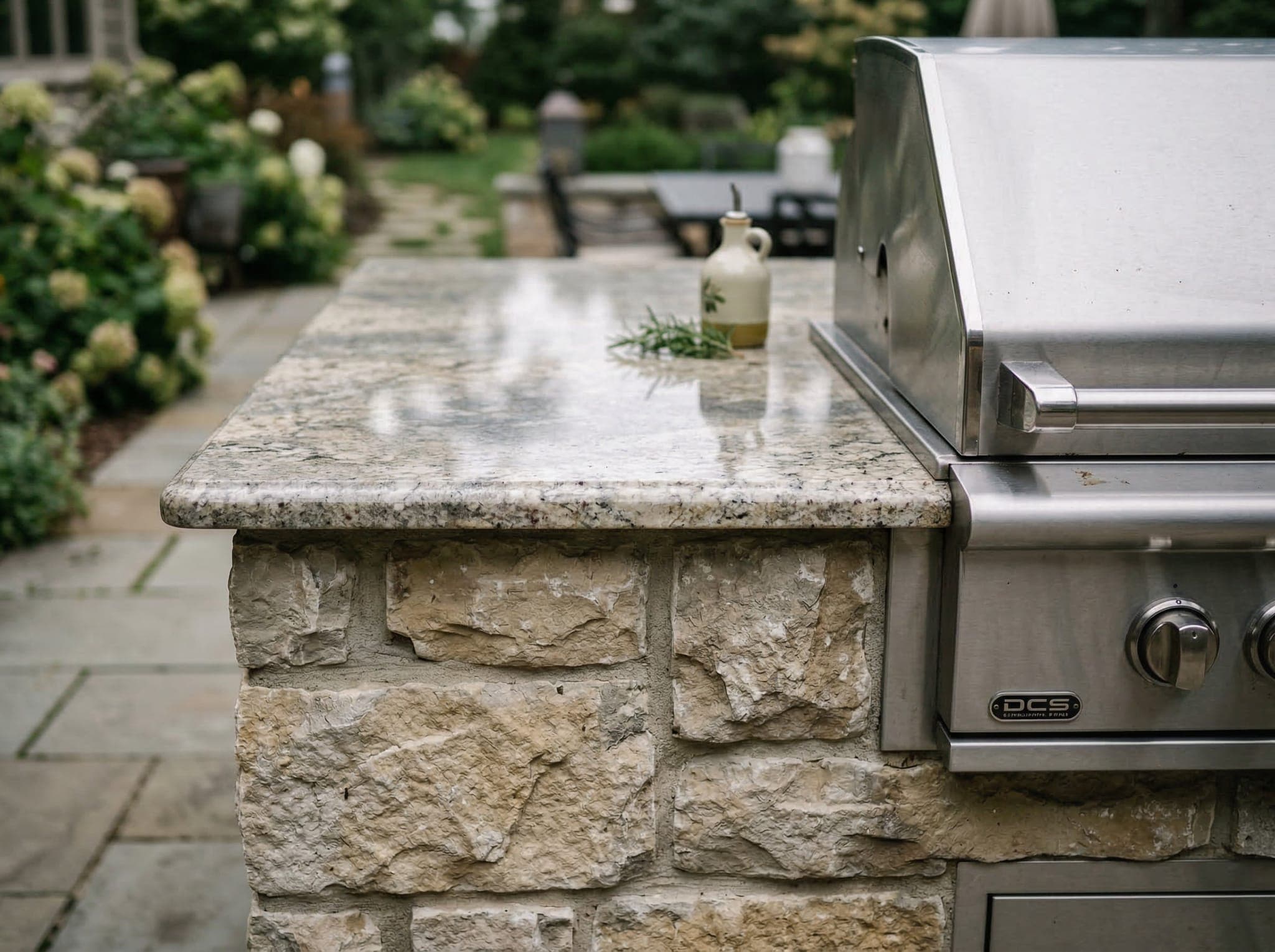 Close-up of outdoor kitchen granite countertop and natural stone veneer on a kitchen island with a built-in grill