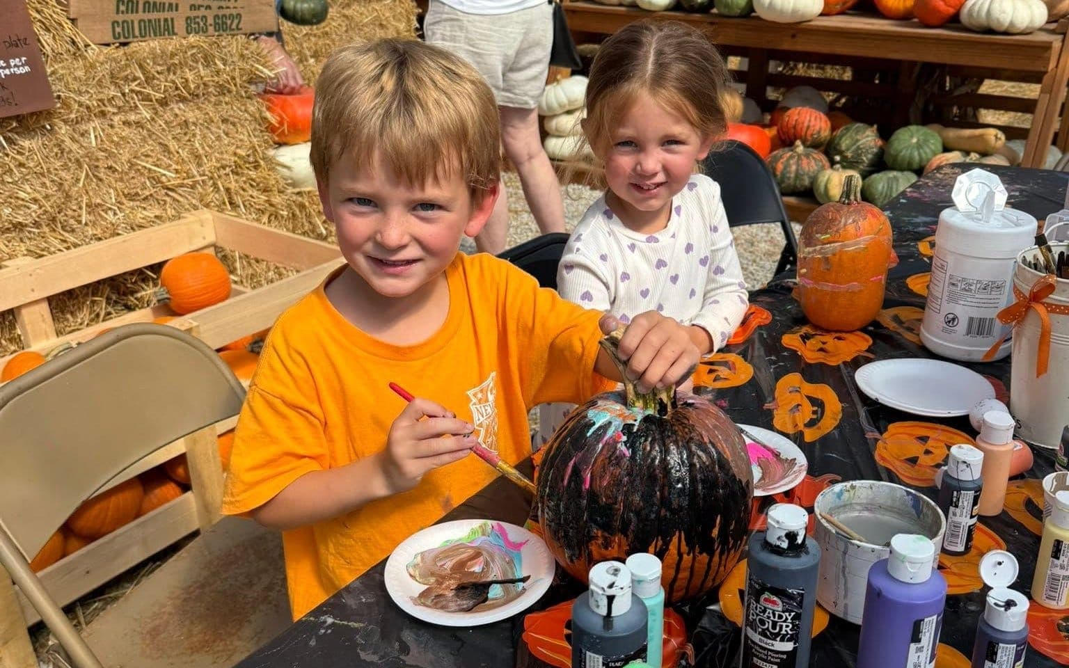 Two children painting pumpkins at the pumpkin painting table during a past Fall Open House