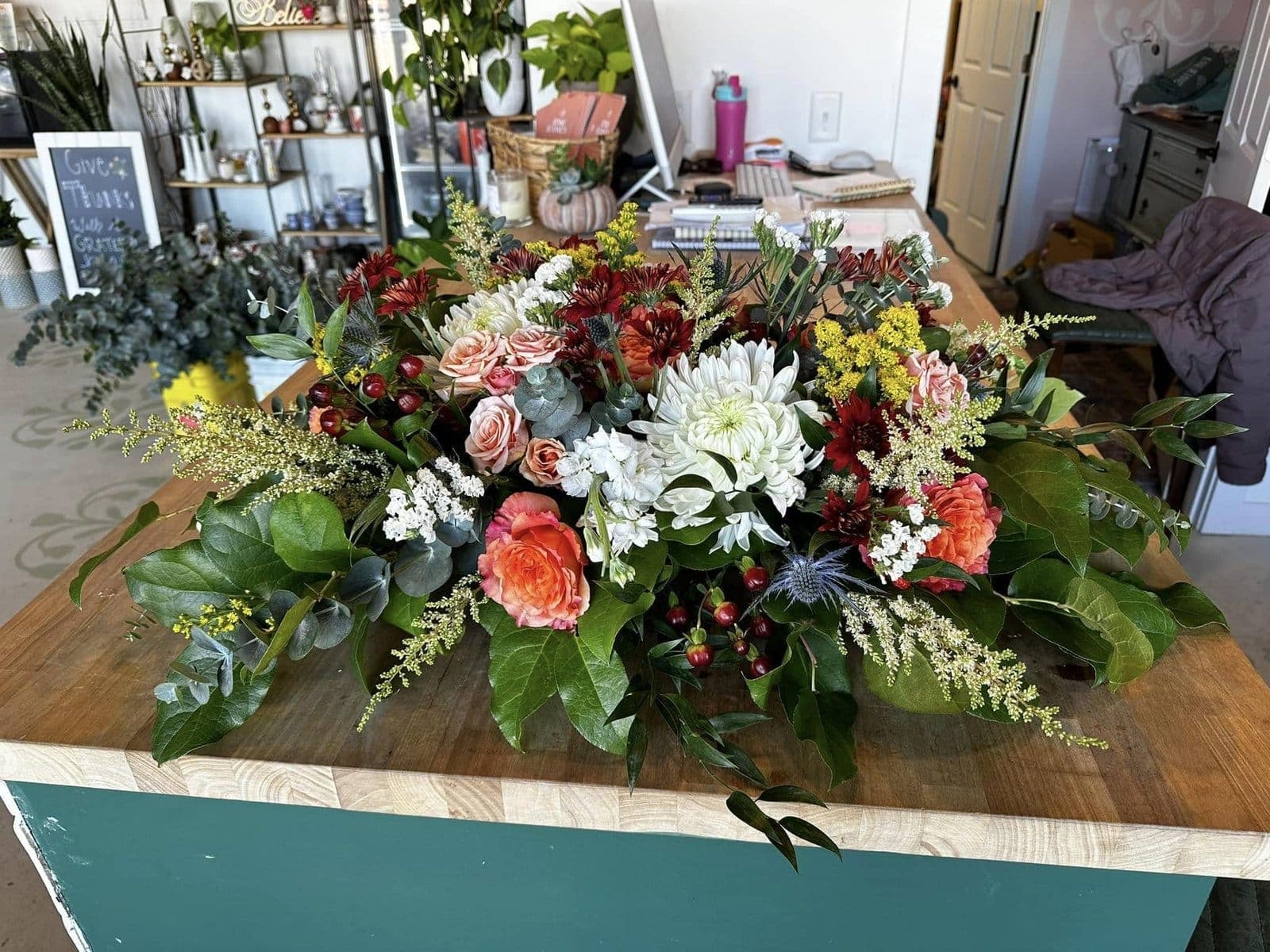 Autumn casket spray of white chrysanthemums, peach roses, and burgundy dahlias