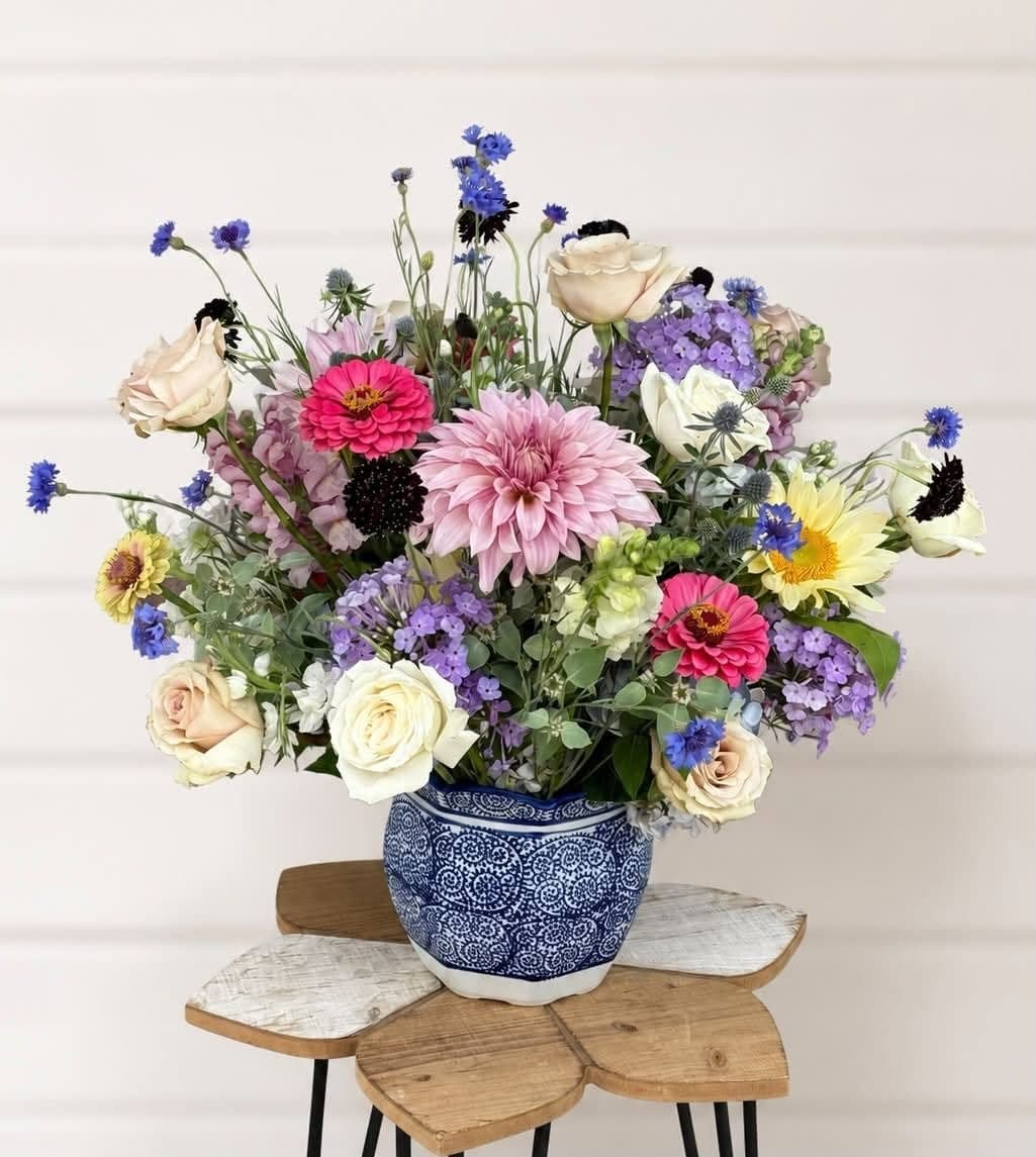 Garden-style arrangement with pink dahlia, zinnias, and cornflower in a blue and white pot