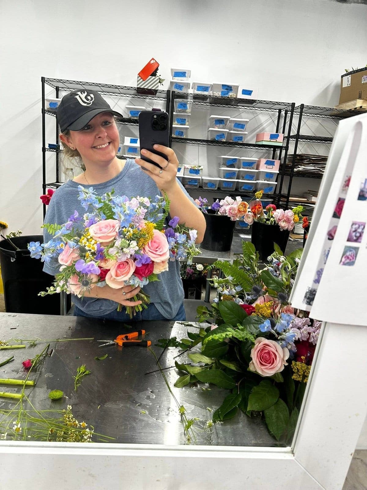 Jesse holding a finished bridal bouquet in the flower shop workroom