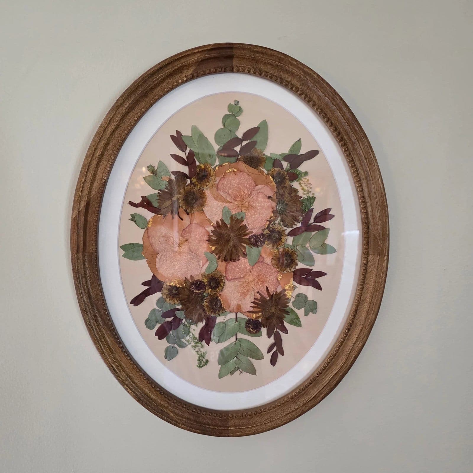 Pressed flower keepsake in an oval wood frame