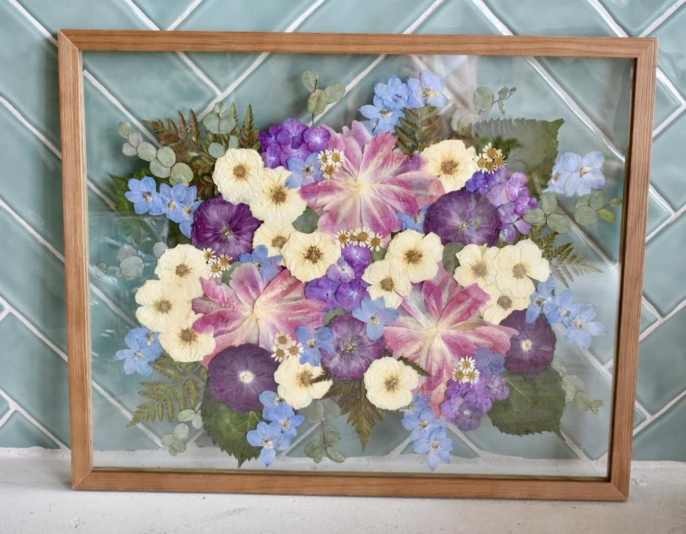 Framed pressed flower keepsake with pink lilies, purple hydrangea, blue delphinium, and cream anemones