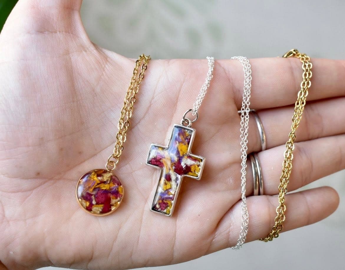 Two resin pendant necklaces, one round and one cross, set with pressed petals