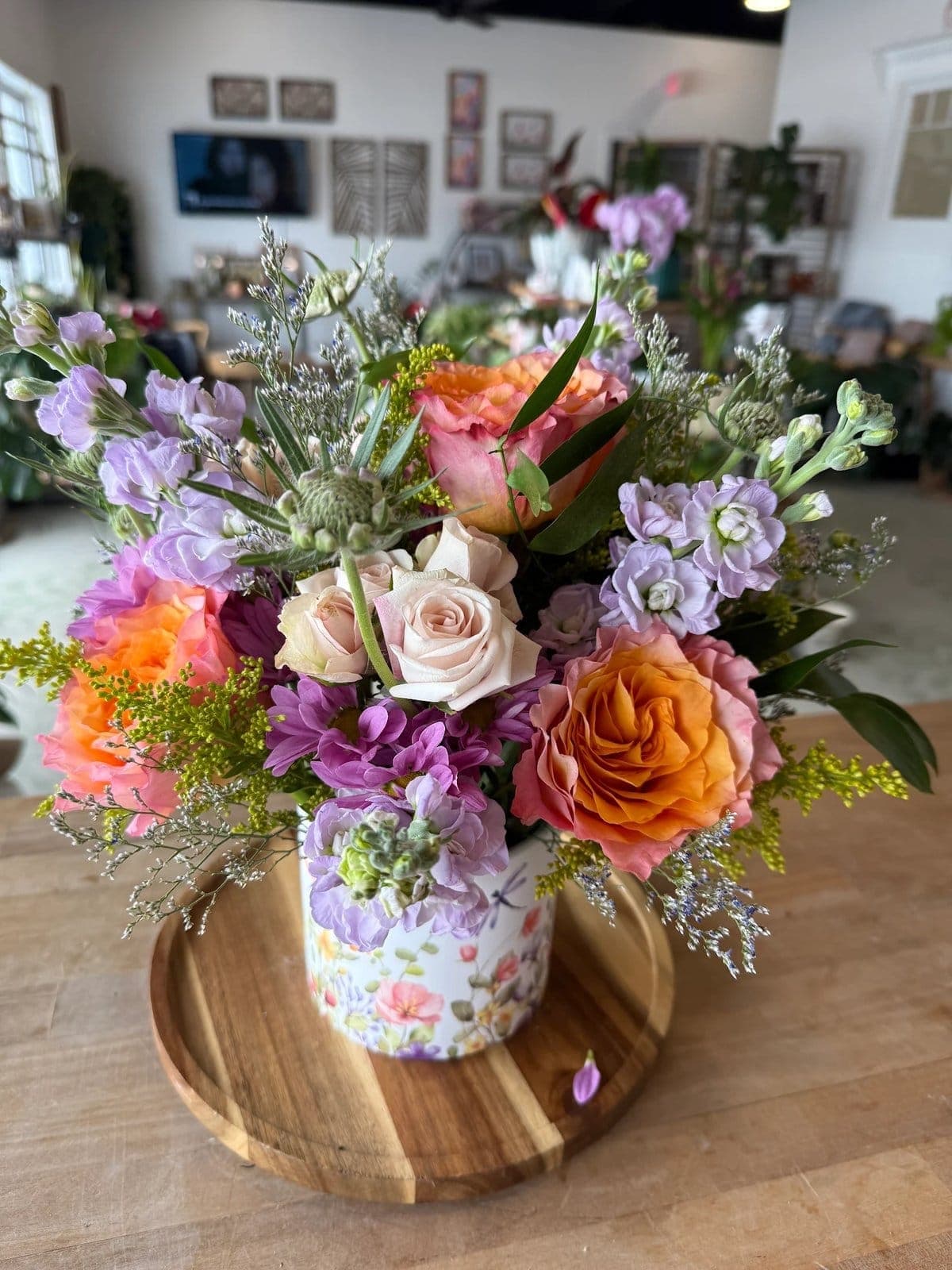 Arrangement of peach roses and lavender stock in a floral ceramic pot