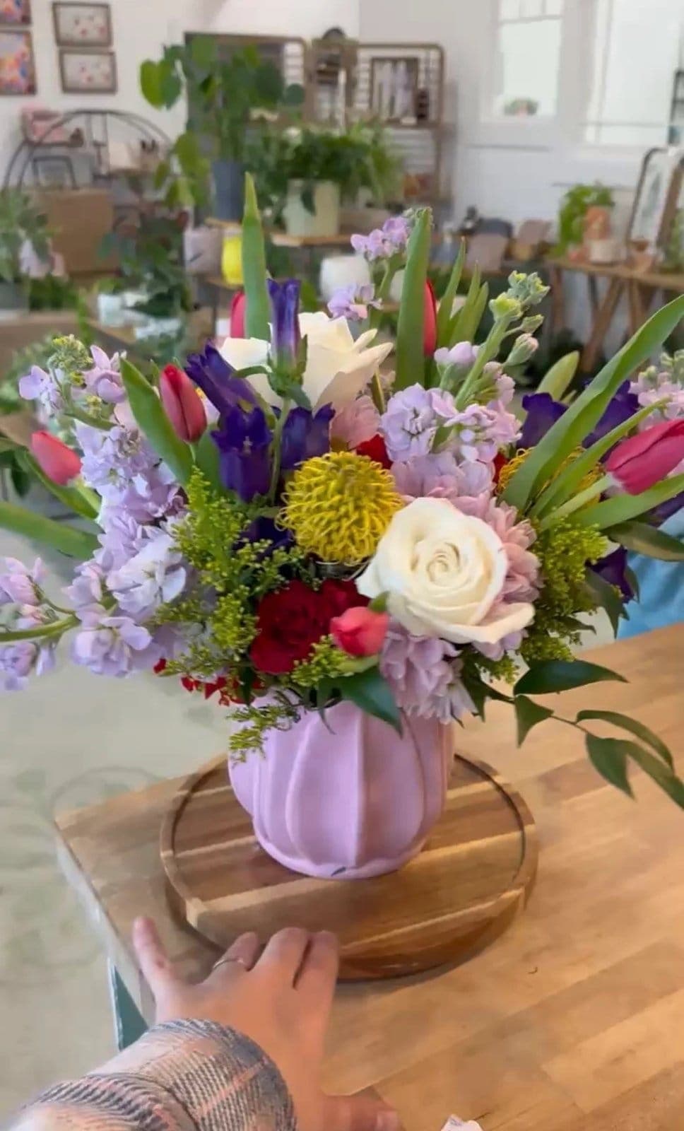 Spring arrangement of tulips, iris, and stock in a pink ceramic vase