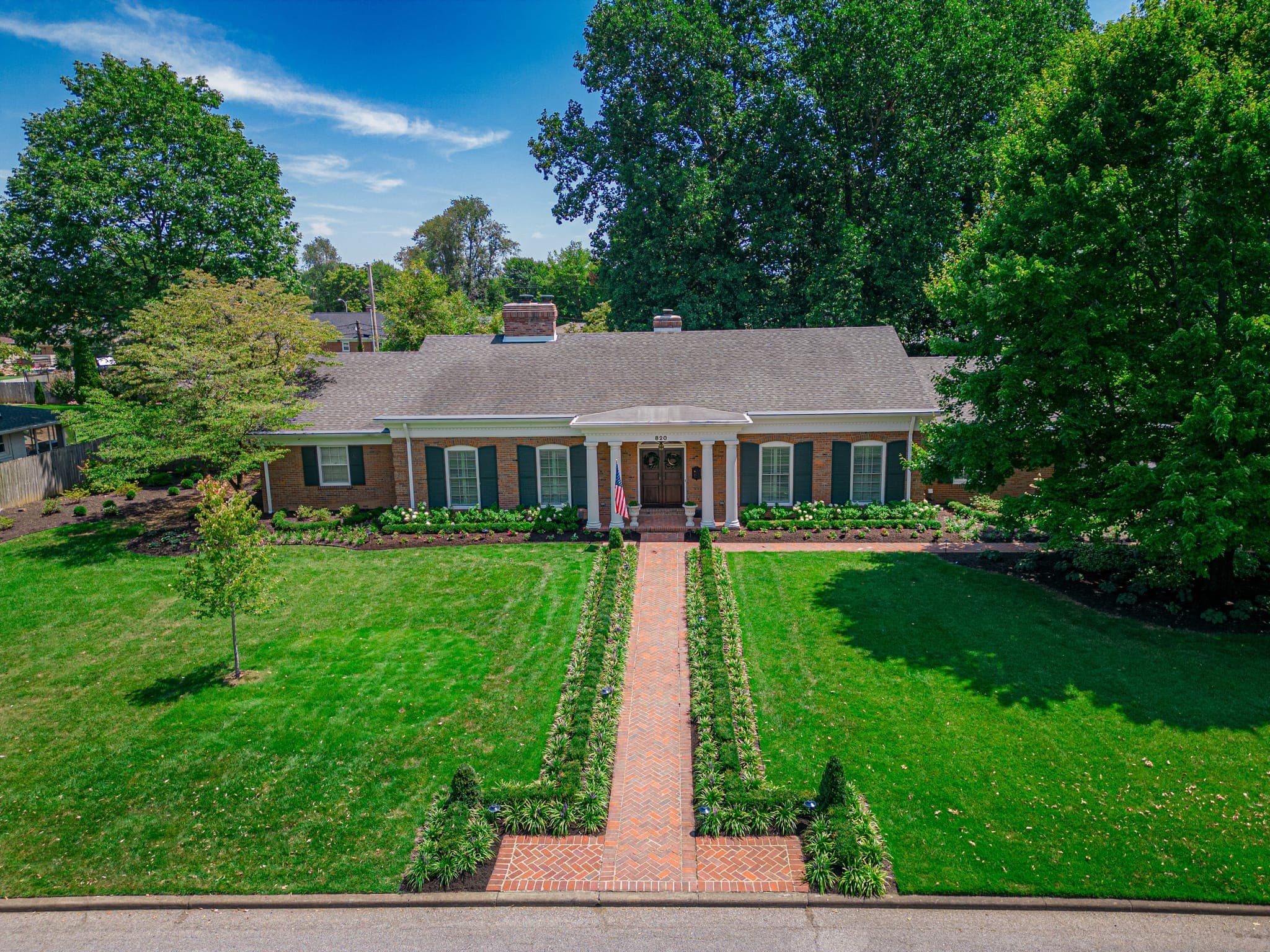 Residential front yard with brick pathway and layered landscaping