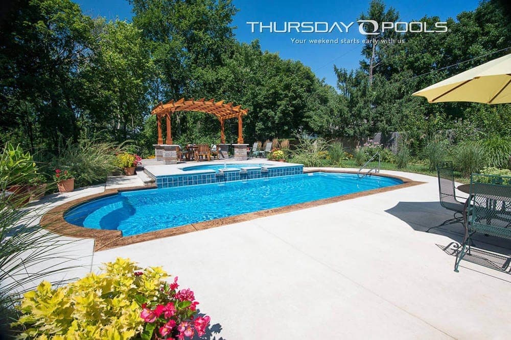 Fiberglass pool with attached raised spa and spillover edge