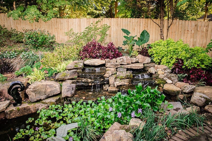 Natural stone waterfall cascading into a landscaped pond